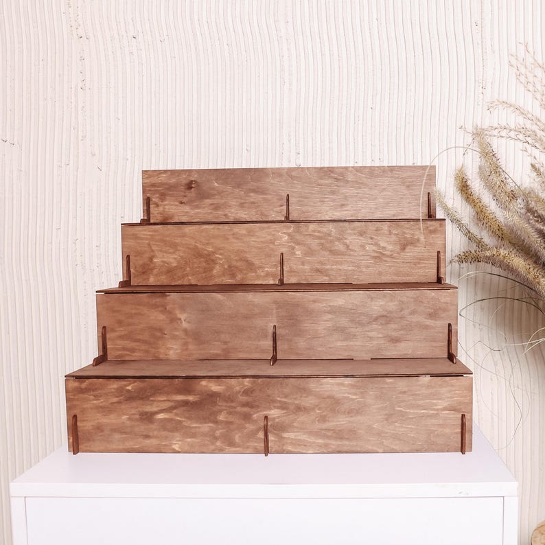 Peut inclure: Pr&eacute;sentoir en bois &agrave; quatre niveaux. Le pr&eacute;sentoir est en bois teint&eacute;, avec un design en gradins. Le grain du bois est visible. Con&ccedil;u pour exposer des objets, chaque niveau offrant une surface.