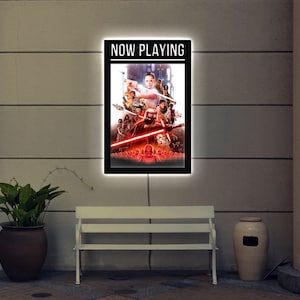 May include: A black framed light-up sign with the words "NOW PLAYING" in white text. The sign features a poster of characters from the Star Wars movie franchise.