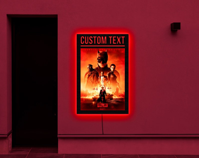 May include: A black framed movie poster with red neon lighting around the border. The poster features a group of characters from the movie "The Batman" with the text "CUSTOM TEXT" at the top.