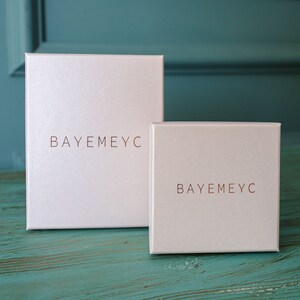 May include: Two white boxes with the text "BAYEMEYC" printed in copper on the front.