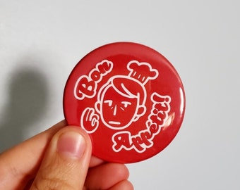 May include: Red round button with a white outline of a chef with a hat and the text "Bon Appetit" in a cursive font.