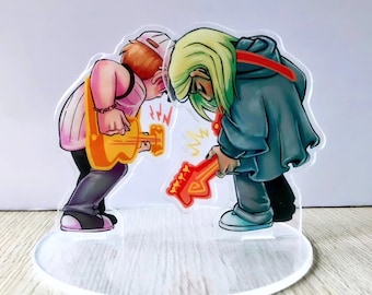 May include: Two cartoon figures, one with green hair and a blue cloak, the other with brown hair and a pink shirt, are playing electric guitars. The figures are on a clear acrylic stand.