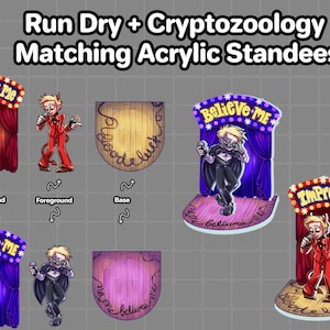 May include: Two acrylic standees featuring cartoon characters in front of a stage. The first standee features a character in a red suit with a devil tail, in front of a red curtain with the words "Impress Me" on top. The second standee features a character in a black suit with a microphone, in front of a purple curtain with the words "Believe Me" on top.