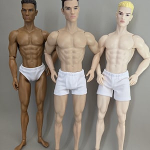 以下が含まれることがあります： 3体の関節可動式男性人形が並んで立っています。左の人形はダークスキンで短いダークヘア、中央の人形はライトスキンでダークヘア、右の人形はフェアスキンでブロンドヘアです。それぞれ白い下着を着用しています。