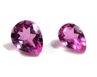 May include: Two pear-shaped pink gemstones with a star-shaped facet pattern.