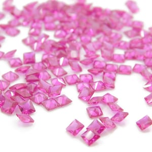 Puede incluir: Una dispersión de piedras preciosas cuadradas de color rosa sobre un fondo blanco.