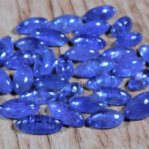May include: A collection of oval-shaped, blue gemstones. The gemstones are smooth and polished, with a slight shimmer.