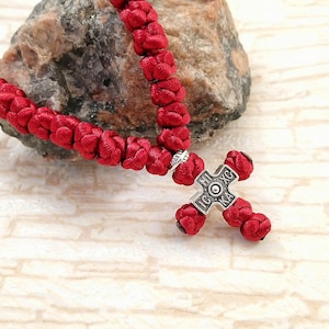 May include: Red prayer rope with a silver cross pendant. The cross has the inscription "IC XC NIKA" in Cyrillic.