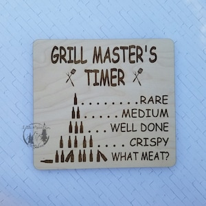 May include: Wooden sign with the text "GRILL MASTER'S TIMER" and grilling icons. The sign has a grilling guide with levels of doneness: Rare, Medium, Well Done, Crispy, and What Meat?