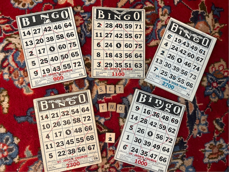 Pu&ograve; includere: Cinque carte da bingo vintage con testo in bianco e nero e numeri rossi. Le carte sono su un tappeto a motivi rossi e blu. Le carte sono della Chiesa di San Giovanni e hanno numeri diversi su ogni carta. Le carte sono per un gioco di bingo.