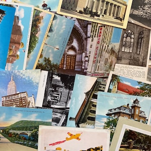 K&ouml;nnte beinhalten: Eine Sammlung von Vintage-Postkarten mit verschiedenen Orten und Geb&auml;uden. Die Postkarten sind in einem zuf&auml;lligen Muster angeordnet, wobei sich einige &uuml;berlappen. Die Postkarten sind in verschiedenen Farben, darunter Blau, Gr&uuml;n, Rot und Wei&szlig;. Die Postkarten sind in gutem Zustand, einige weisen Gebrauchsspuren auf.