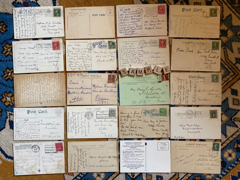 May include: A collection of vintage postcards, some with handwritten messages, others with printed images. The postcards are arranged in a grid pattern on a patterned surface. The postcards are in various states of wear and tear, with some showing signs of age and use.