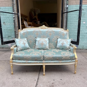 May include: A light blue and gold two-seater sofa with a floral pattern and carved wooden legs.