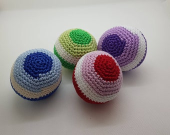 Könnte beinhalten: Vier farbenfrohe gehäkelte Jonglierbälle. Jeder Ball hat ein anderes Farbschema: blau, grün, rot und lila. Die Bälle sind rund mit einem Spiralmuster oben und Streifen in der Mitte.