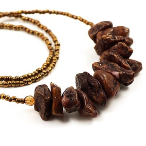 May include: A brown beaded necklace with a long strand of small gold beads and a shorter strand of larger, irregularly shaped brown beads.