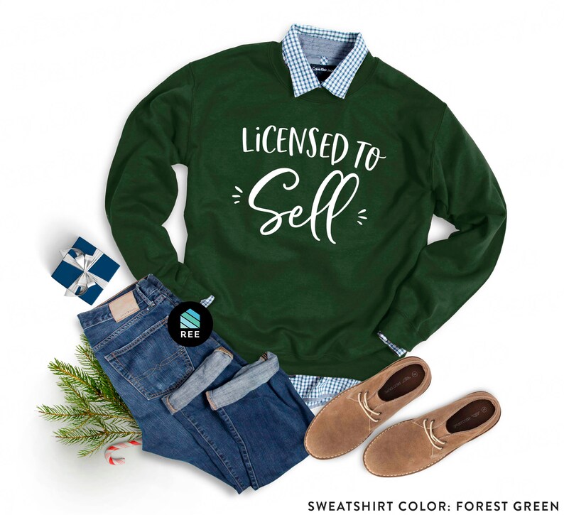 May include: A forest green sweatshirt with the text "Licensed to Sell" in white lettering. The sweatshirt is paired with blue jeans, a plaid shirt, and brown leather shoes.