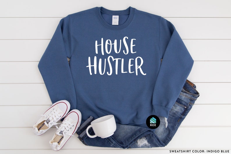 Peut inclure: Sweat-shirt bleu indigo avec le texte "HOUSE HUSTLER" en blanc. Le sweat-shirt est associ&eacute; &agrave; des baskets blanches, une tasse blanche et un jean bleu. Le sweat-shirt est de style col rond.