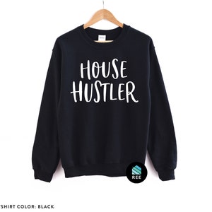 Peut inclure: Sweat-shirt noir avec le texte blanc "HOUSE HUSTLER". Le haut &agrave; manches longues est suspendu &agrave; un cintre en bois. Le sweat-shirt est de couleur noire unie.