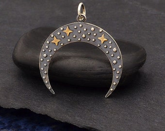 May include: A silver crescent moon pendant with a textured surface and four gold stars. The pendant is on a dark gray background.