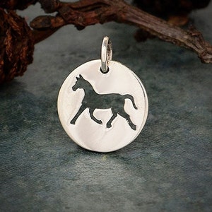 May include: Silver charm with a cutout silhouette of a horse running. The charm is round and has a smooth, polished finish.