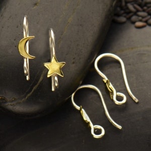 May include: A set of three silver earring hooks. Two of the hooks have a gold crescent moon and a gold star charm attached. The third hook is plain.