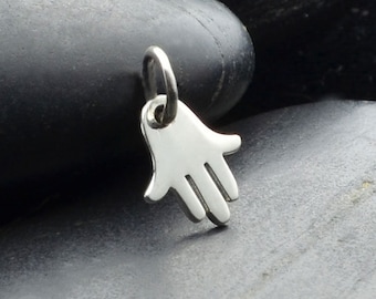 Puede incluir: Un amuleto de plata en forma de mano de Hamsa, símbolo de protección y buena suerte.