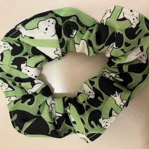 Op de afbeelding: Groene stoffen haarband met een patroon van witte geesten en zwarte katten.