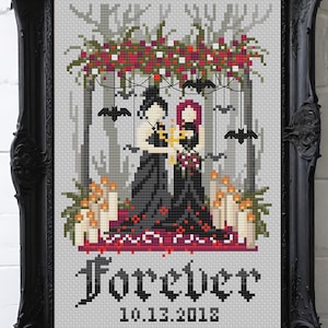 Peut inclure: Une broderie au point de croix dans un cadre noir orné représentant deux silhouettes en robes noires sous une arche florale avec des chauves-souris, des bougies et des pétales rouges. Le texte indique Forever 10.13.2018 et ByMegC en orange.