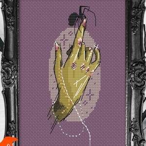 May include: Cross-stitch art in a black ornate frame. The artwork features a green hand with pink nails, bandages, and a white thread. The background is a purple cross-stitch pattern. The artist's logo, "ByMegC", is in the lower left corner.