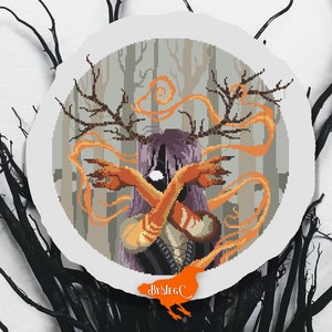 May include: Cross-stitch pattern featuring a woman with antlers and orange flames in a forest setting. The pattern is in a circular frame with the text "ByMEG.C" at the bottom.