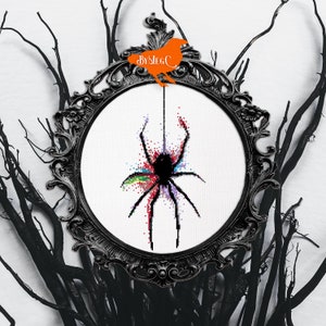May include: A black spider with colorful accents is hanging from a web in a black ornate frame. The frame is against a white background with black branches.