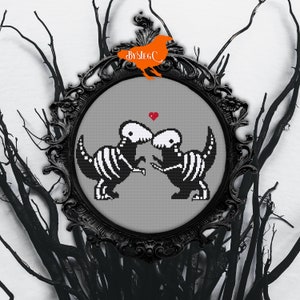 May include: Cross-stitch pattern of two skeleton dinosaurs kissing with a red heart above them. The pattern is framed in a black ornate frame.