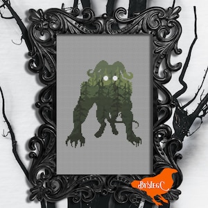 Peut inclure: Motif de point de croix d'un monstre vert aux yeux blancs brillants, debout dans une forêt. Le monstre est en silhouette sur un fond gris. Le motif est encadré dans un cadre noir orné.