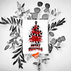 May include: A white card featuring a red and black Christmas tree design. The tree is decorated with candy canes, eyeballs, and a skull. The text "Merry Creepmas" is written in red dripping letters below the tree.