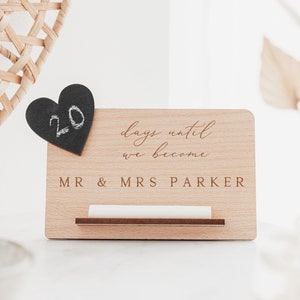 May include: Wooden countdown sign with the text "days until we become MR & MRS PARKER" and a chalkboard heart with the number 20 written on it.