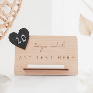 May include: A wooden countdown sign with a black heart-shaped chalkboard that says "20" and the text "days until ANY TEXT HERE".