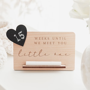 May include: Wooden sign with the text "Weeks until we meet you little one" and a chalkboard heart that says "15".
