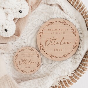 May include: Two wooden baby announcement signs with the text "HELLO WORLD MY NAME IS Ottilie ROSE" surrounded by a floral wreath. A white crocheted bunny and a white crocheted bunny head are also in the image.