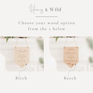Op de afbeelding: Twee houten borden met een rustieke uitstraling, een met de tekst "Santa Please Stop Here For Lily" en de andere met de tekst "Father Christmas Please Stop Here For Thomas". De borden hangen aan een touwtje en zijn onderaan gelabeld met "Birch" en "Beech".