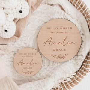 May include: Two wooden baby announcement plaques with the text "Hello World, My Name Is Amelie Grace" and a floral design.