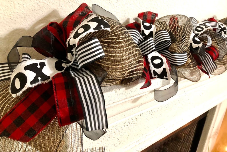 May include: A black, white, and red Christmas swag with burlap and mesh. The swag has a "XO" design on it.