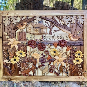 May include: A wooden relief carving featuring a detailed landscape scene. The artwork depicts a cabin, birds, flowers, and butterflies. The color palette includes various shades of brown, yellow, and red, with a natural wood frame.