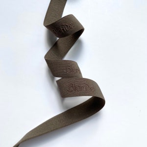 May include: A brown elastic band with the word "Stone" embroidered on it.
