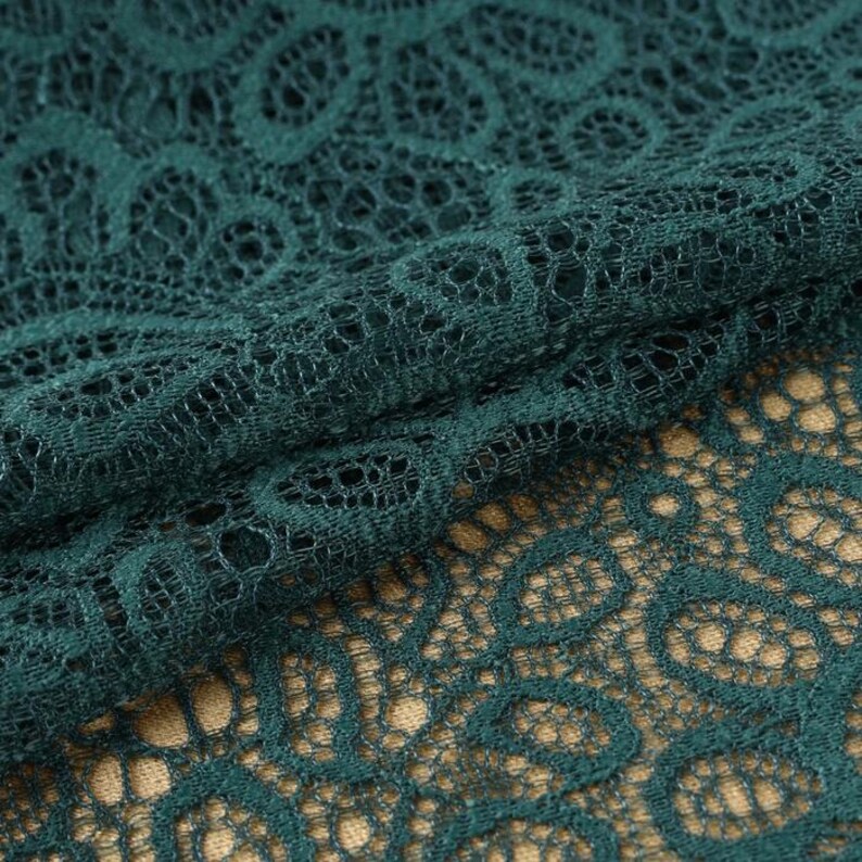 Op de afbeelding: Teal groene kantstof met een delicaat bloemenpatroon. De kant is zacht en doorschijnend, waardoor het perfect is voor een verscheidenheid aan knutselprojecten.