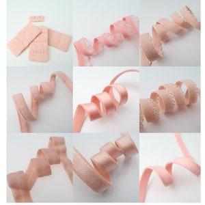 May include: Assortment of pink elastic bra straps with different textures and styles. Some straps have a scalloped edge, while others are smooth. The straps are all approximately 1 inch wide.