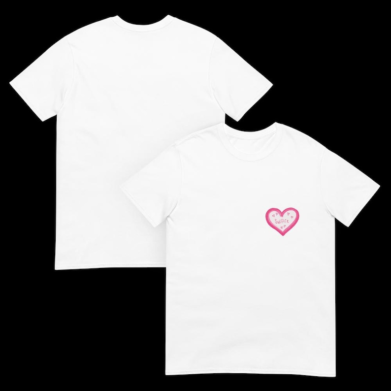 May include: Two white t-shirts. One shirt has a pink heart graphic with the word "sweetie" inside. The heart has a pink outline and is filled with small pink hearts. The other shirt is plain.