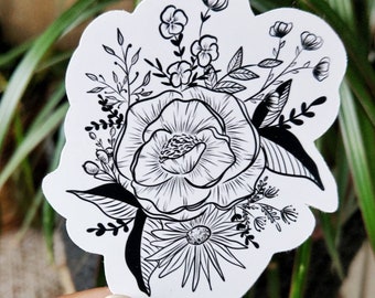 May include: Black and white line art sticker of a bouquet of flowers. The bouquet features a large flower with a center and petals, surrounded by smaller flowers and leaves.