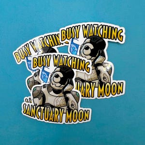 May include: A collection of stickers featuring a cartoon astronaut with the text "Busy Watching Sanctuary Moon" in a yellow and white font. The astronaut is wearing a white and gray spacesuit with a black helmet.