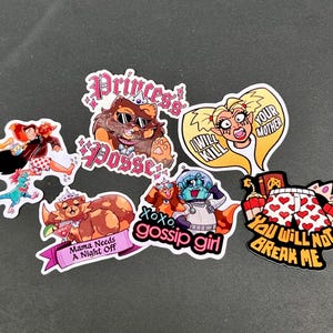 May include: A collection of colorful stickers with cartoon illustrations and text. The stickers feature various designs, including a cat wearing sunglasses, a woman with a speech bubble, and text that reads "Mama Needs A Night Off" and "You Will Not Break Me."