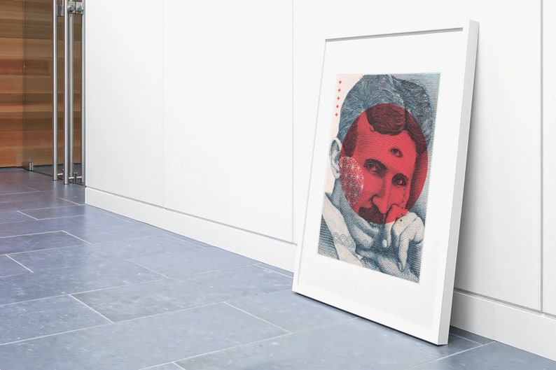 May include: A framed print of a portrait of Nikola Tesla with a red circle over his face. The circle has a third eye in the centre. The print is in a white frame and is leaning against a white wall.